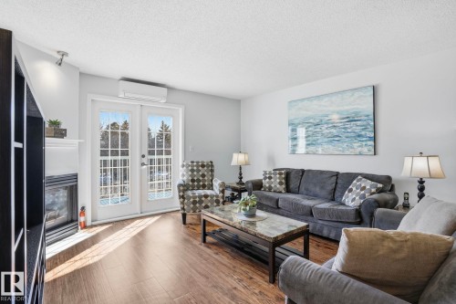 Living area featuring wood-finish flooring, a fireplace with a white mantel, and French doors - 309 20 Grange Drive, St. Albert, AB - Indoor Photo Showing Living Room With Fireplace