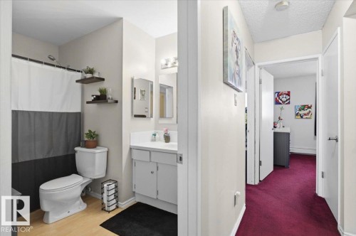 Bathroom featuring a shower with a white and gray curtain, a white toilet, and a vanity with a white countertop - 6 3803 76 Street, Edmonton, AB - Indoor Photo Showing Bathroom