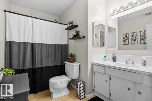 Bathroom featuring a white vanity with an integrated sink, polished chrome faucet, and a large mirror - 6 3803 76 Street, Edmonton, AB - Indoor Photo Showing Bathroom