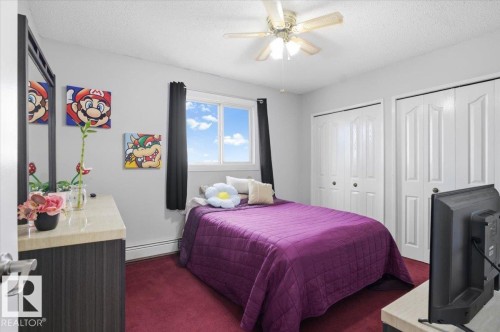 Bright room featuring a window with black curtains, a ceiling fan, and two white bi-fold closet doors - 6 3803 76 Street, Edmonton, AB - Indoor Photo Showing Bedroom