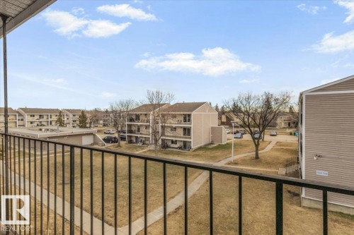 Exterior balcony with black metal railings overlooking a landscaped common area with paved walkways, mature trees, and surrounding multi-story residential buildings - 6 3803 76 Street, Edmonton, AB - Outdoor With Balcony