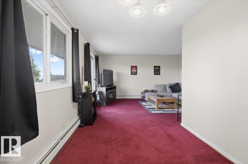 Living area featuring wall-to-wall red carpet, baseboard heating, multiple windows, and a ceiling light fixture - 6 3803 76 Street, Edmonton, AB - Indoor Photo Showing Other Room