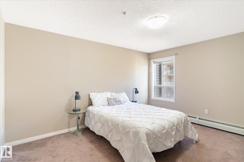 Bedroom featuring neutral wall paint, carpet flooring, a single window, white trim, and a baseboard radiator - 203 155 Edwards Drive, Edmonton, AB - Indoor Photo Showing Bedroom