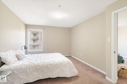 Bedroom featuring a window with white trim, beige wall paint, carpet flooring, a flush-mount ceiling light, and white baseboards - 203 155 Edwards Drive, Edmonton, AB - Indoor Photo Showing Bedroom