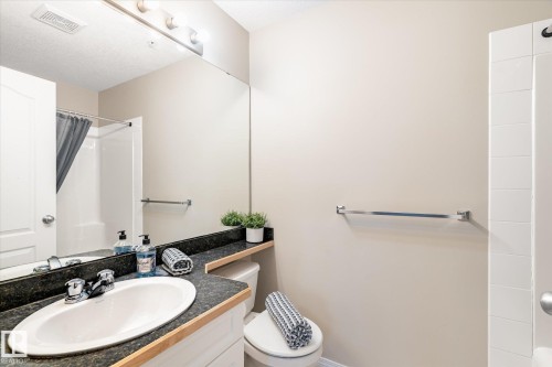 Bathroom featuring a vanity with an integrated sink, dark countertop, and a large wall-mounted mirror - 203 155 Edwards Drive, Edmonton, AB - Indoor Photo Showing Bathroom