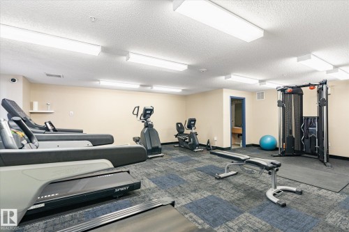 Fitness center featuring multiple treadmills, exercise bikes, a weight bench, and a cable machine - 203 155 Edwards Drive, Edmonton, AB - Indoor Photo Showing Gym Room