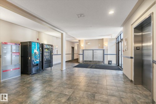 Building lobby featuring tile flooring, recessed lighting, wall-mounted mailboxes, and an elevator with a brushed metal finish - 203 155 Edwards Drive, Edmonton, AB - Indoor Photo Showing Other Room