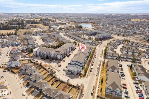 Aerial perspective showcasing a multi-story residential building with grey roofing and light-colored facades - 203 155 Edwards Drive, Edmonton, AB - Outdoor With View