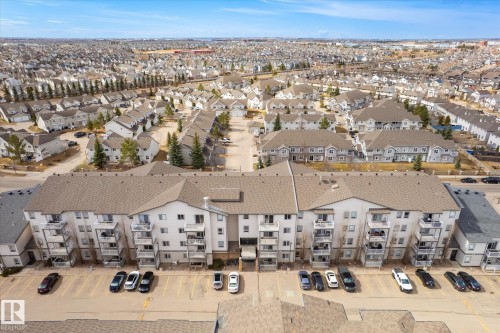 Multi-story residential building featuring private balconies, individual entryways, and an expansive parking area - 203 155 Edwards Drive, Edmonton, AB - Outdoor With View