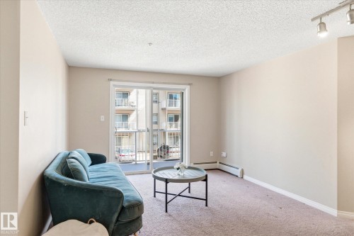 Living area featuring neutral wall tones, textured ceiling, and track lighting - 203 155 Edwards Drive, Edmonton, AB - Indoor