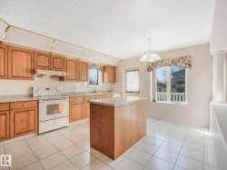 Kitchen featuring wood-finish cabinetry, light-toned countertops, and a white tile backsplash - 
