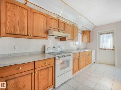 Kitchen featuring wood cabinetry, white tiled flooring, a white tile backsplash, light-colored countertops, and a white freestanding range - 