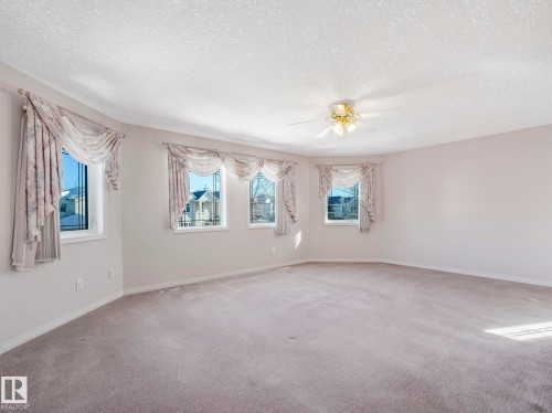 Spacious room featuring carpet flooring, multiple windows, a ceiling fan with integrated lighting, and neutral wall tones - 1054 Ormsby Crescent, Edmonton, AB - Indoor Photo Showing Other Room