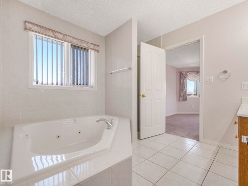 Corner soaking tub with integrated jets and chrome fixtures - 1054 Ormsby Crescent, Edmonton, AB - Indoor Photo Showing Bathroom