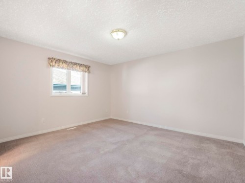 Spacious room featuring neutral carpeting, light-colored walls, and a textured ceiling - 1054 Ormsby Crescent, Edmonton, AB - Indoor Photo Showing Other Room