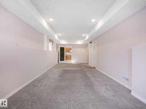 Expansive finished room featuring textured carpeting, recessed lighting, white trim, and a partial wall element - 1054 Ormsby Crescent, Edmonton, AB - Indoor Photo Showing Other Room
