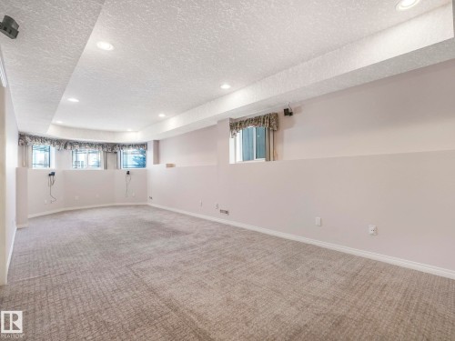 Spacious carpeted room featuring a drop ceiling with recessed lighting, multiple windows, and light-toned walls - 1054 Ormsby Crescent, Edmonton, AB - Indoor Photo Showing Other Room