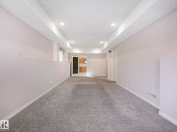 Expansive finished room featuring textured carpeting, recessed lighting, white trim, and a partial wall element - 