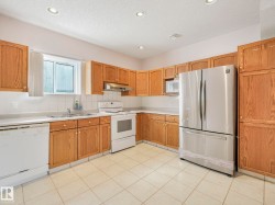 Kitchen featuring wood cabinetry, white appliances, a stainless steel refrigerator, tile flooring, and recessed lighting - 