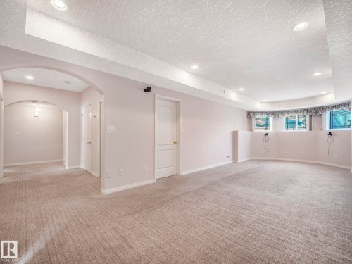 Spacious carpeted room featuring recessed lighting, an arched doorway, and multiple windows - 1054 Ormsby Crescent, Edmonton, AB - Indoor Photo Showing Other Room