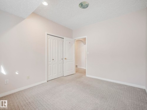 Neutral-toned room featuring a light gray textured carpet, white baseboards, and bi-fold closet doors - 1054 Ormsby Crescent, Edmonton, AB - Indoor Photo Showing Other Room