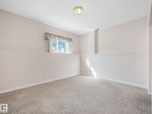 Carpeted room featuring a window with natural light, light-toned walls, white baseboards, and a flush-mount ceiling light fixture - 1054 Ormsby Crescent, Edmonton, AB - Indoor Photo Showing Other Room