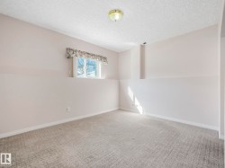 Carpeted room featuring a window with natural light, light-toned walls, white baseboards, and a flush-mount ceiling light fixture - 