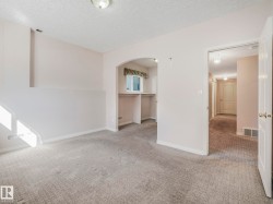 Carpeted room featuring an arched alcove with built-in shelving, a window, and a light-toned wall finish - 
