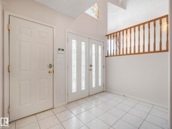 Entryway featuring white tile flooring and a double entry door with decorative glass inserts - 