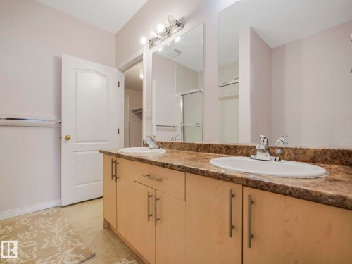 Dual vanity with a granite-finish countertop, light wood cabinetry, and integrated white oval sinks - 1054 Ormsby Crescent, Edmonton, AB - Indoor Photo Showing Bathroom