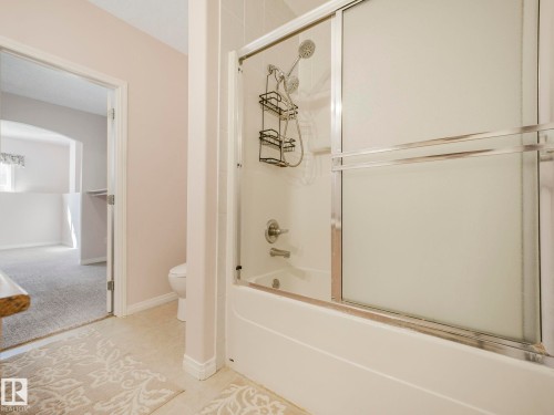 Shower-over-tub combination with sliding frosted glass doors and chrome hardware - 1054 Ormsby Crescent, Edmonton, AB - Indoor Photo Showing Bathroom