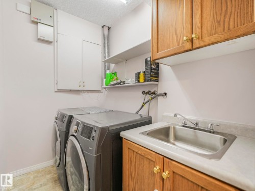 Utility room featuring a built-in sink with countertop, wood cabinetry, and overhead storage shelving - 1054 Ormsby Crescent, Edmonton, AB - Indoor Photo Showing Laundry Room