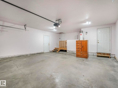 Spacious garage featuring a concrete floor, multiple entry points, and an overhead garage door opener - 1054 Ormsby Crescent, Edmonton, AB - Indoor Photo Showing Garage