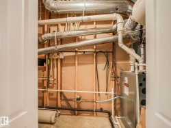Utility closet with exposed ductwork, piping, and a visible furnace unit - 