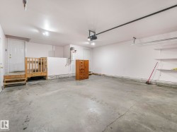 Spacious garage featuring a concrete floor, bright overhead lighting, and white painted walls - 