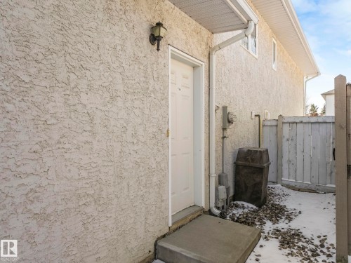 Stucco exterior featuring a white door and an exterior wall light fixture - 1054 Ormsby Crescent, Edmonton, AB - Outdoor With Exterior
