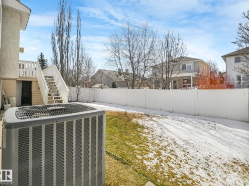 Private backyard featuring a white vinyl privacy fence and a two-story exterior with an upper-level deck - 1054 Ormsby Crescent, Edmonton, AB - Outdoor