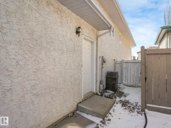 Exterior stucco siding with a single white entry door - 