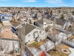 Rear elevation featuring a multi-level deck, white railing, and a ground-level patio with a fire pit - 