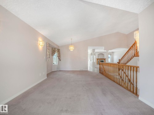 Vaulted ceiling room with recessed bay windows, chandelier lighting, wall sconces, and a wood spindle railing - 1054 Ormsby Crescent, Edmonton, AB - Indoor Photo Showing Other Room