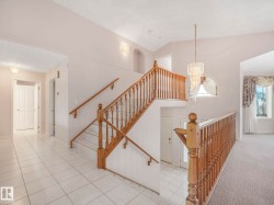 Multi-level interior featuring a grand staircase with wood banisters, decorative chandelier, and arch window - 