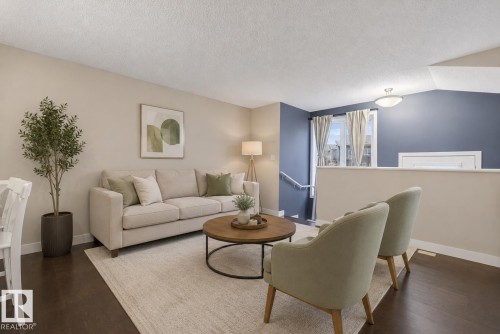 Spacious living area featuring dark wood-finish flooring, a neutral paint palette, and an accent wall - 45 4470 Prowse Road, Edmonton, AB - Indoor Photo Showing Living Room