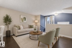 Spacious living area featuring dark wood-finish flooring, a neutral paint palette, and an accent wall - 