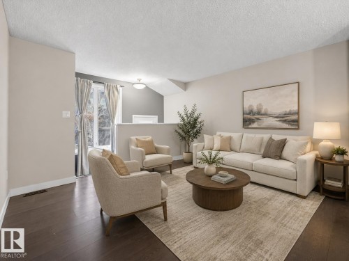 Bright living area featuring dark wood-finish flooring and light neutral wall tones - 45 4470 Prowse Road, Edmonton, AB - Indoor Photo Showing Living Room