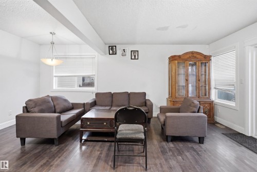 Spacious living area featuring wood-finish flooring, white walls, and a contemporary ceiling light fixture - 3545 11 Street, Edmonton, AB - Indoor Photo Showing Living Room