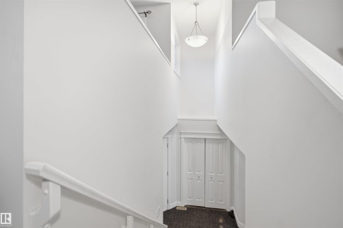 Two-story interior featuring a contemporary pendant light fixture, white painted walls, and bi-fold doors - 3545 11 Street, Edmonton, AB - Indoor Photo Showing Other Room