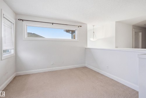 Bright room featuring a horizontal window, an additional window with blinds, and light carpet flooring - 3545 11 Street, Edmonton, AB - Indoor Photo Showing Other Room