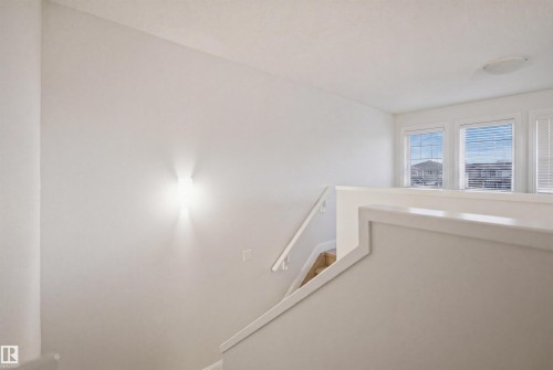 Upper-level landing featuring a white painted railing, three multi-pane windows with horizontal blinds, and a flush-mount ceiling light fixture - 3545 11 Street, Edmonton, AB - Indoor Photo Showing Other Room