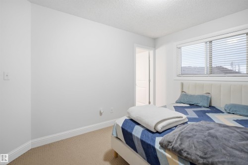 Bedroom featuring a large window with blinds, light-colored carpeting, white walls, and white baseboards - 3545 11 Street, Edmonton, AB - Indoor Photo Showing Bedroom