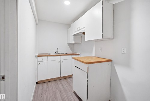 Compact kitchen featuring white cabinetry and wood-finish countertops - 3545 11 Street, Edmonton, AB - Indoor Photo Showing Kitchen With Double Sink